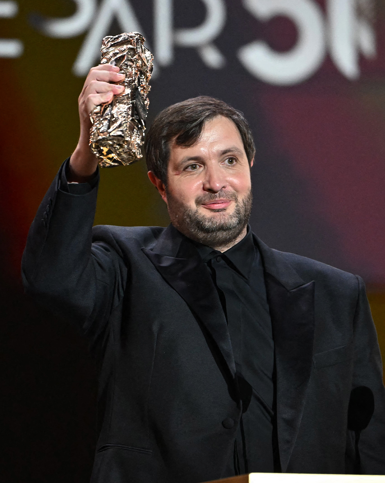 Karim Leklou reçoit le prix du meilleur acteur pour le film Le Roman de Jim (2024) lors de la 50e édition de la cérémonie des César à l'Olympia, le 28 février 2025 © BERTRAND GUAY/AFP via Getty Images.