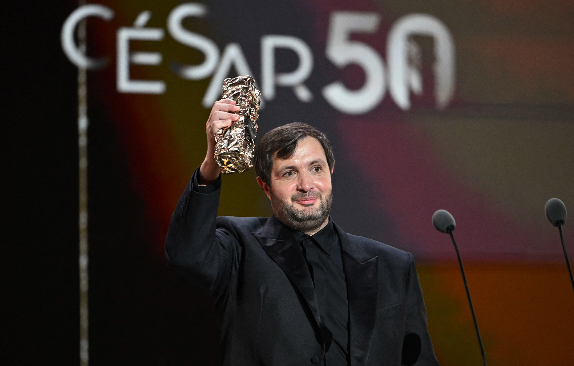 Karim Leklou reçoit le prix du meilleur acteur pour le film Le Roman de Jim (2024) lors de la 50e édition de la cérémonie des César à l'Olympia, le 28 février 2025 © BERTRAND GUAY/AFP via Getty Images.